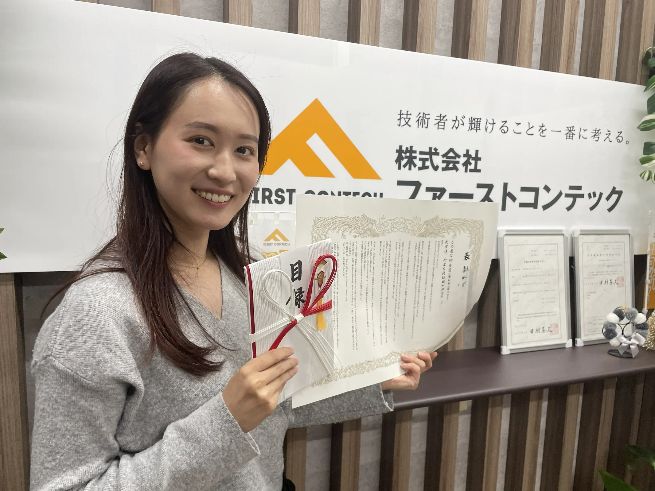 表彰状を手に笑顔で写るファーストコンテックの社員