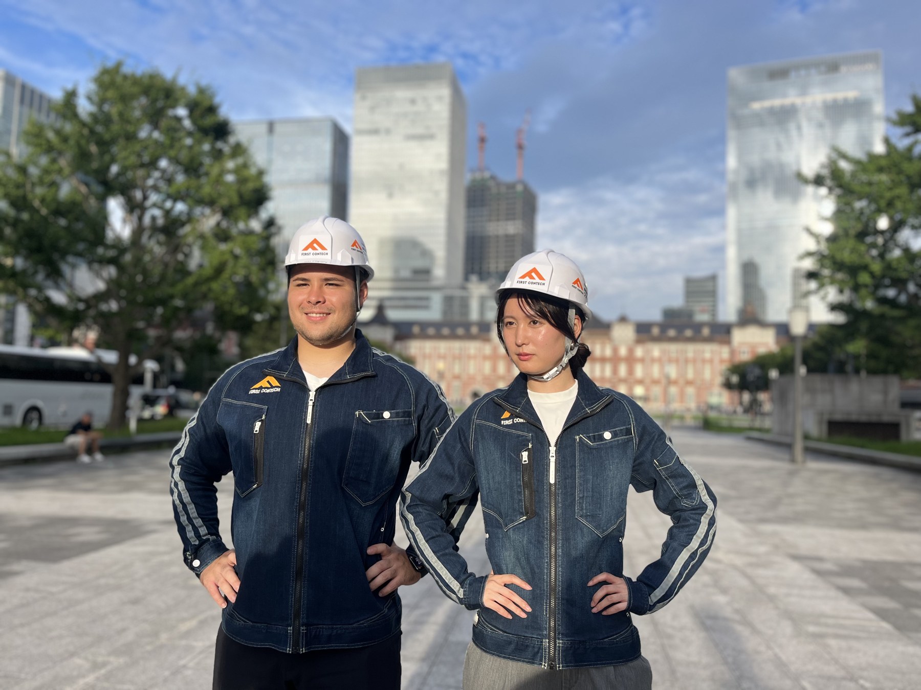 FC社員が東京駅前でヘルメットと作業着を着て立つ写真